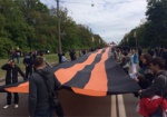 По улице Сумской идет шествие с большой георгиевской лентой